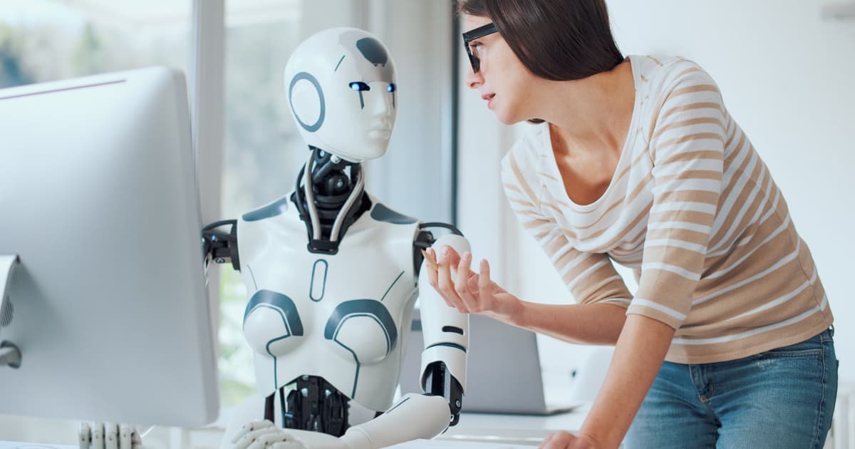 Kobieta i humanoidalny robot AI patrzą razem na ekran komputera - agent AI jako drugi użytkownik treści w sieci